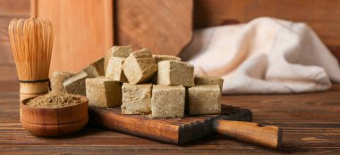 Lezzetli hojicha marşmelovları, pudra ve şampanyalı tahta arka planda.