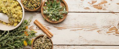 Beyaz ahşap zemin üzerinde farklı kurutulmuş otlar ve çiçekler ve metin için yer var.