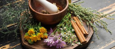 Koyu ahşap arka planda farklı otlar taşıyan havan topu.