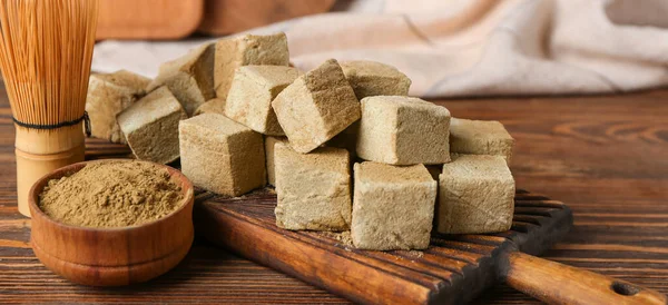 Lezzetli hojicha marşmelovları, pudra ve şampanyalı tahta arka planda.