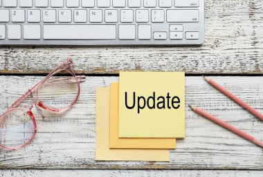 PC klavye, gözlükler, kalemler ve üzerinde kelime UPDATE olan not kağıdı.