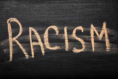 Word RACISM written on blackboard