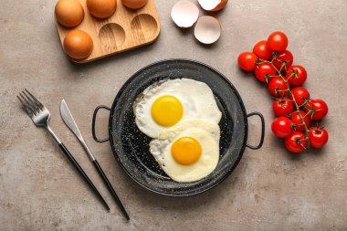 Lezzetli yumurtalı tava, domates ve arkaplanda çatal bıçak.