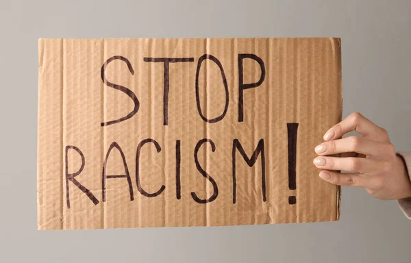 Χέρι Κρατώντας Κομμάτι Του Χαρτοκιβωτίου Κείμενο Stop Racism Γκρι Φόντο — Φωτογραφία Αρχείου