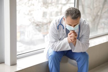 Klinikte dua eden olgun erkek doktor.