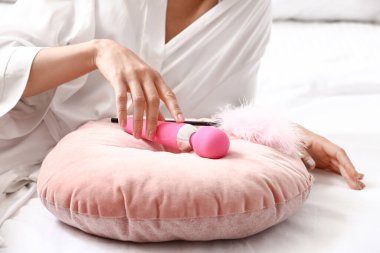 Yatak odasında vibratörü ve tüy sopası olan genç bir kadın.