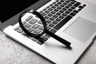 Laptop and magnifier on light background. Concept of search