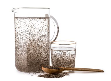 Beyaz zemin üzerinde chia tohumları olan sürahi ve bir bardak su.