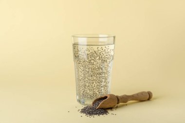 Bir bardak su ve kepçeyle arkaplanda chia tohumları