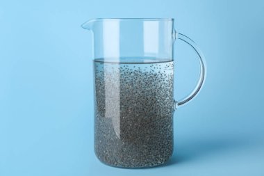 Renk arkaplanında chia tohumları olan cam sürahi su