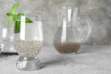 Chia tohumlu bir bardak su ve arka planda taze nane.
