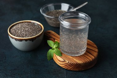 Sağlıklı bir bardak, tahta üzerinde chia tohumu olan koyu arkaplan.
