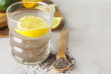 Chia tohumlu bir bardak su, arka planda limon dilimi ve kaşık, yakın plan.