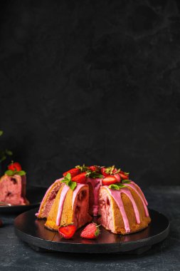 Wooden board with tasty strawberry cake on dark background