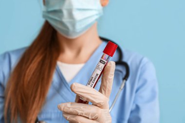 Mavi arka planda maymun çiçeği virüsü örneği olan doktor, yakın plan.