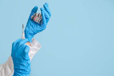 Mavi arka planda maymun çiçeği aşısı ve şırıngası olan doktorun elleri