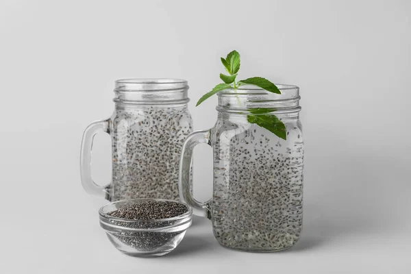 Mason jars of water and chia seeds on light background