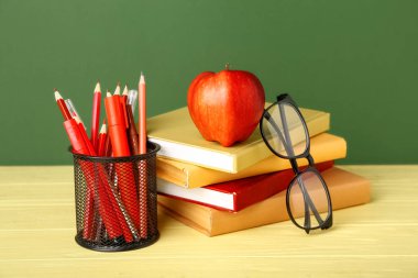 Yeşil arka planda elma ve gözlüklü okul kırtasiyesi