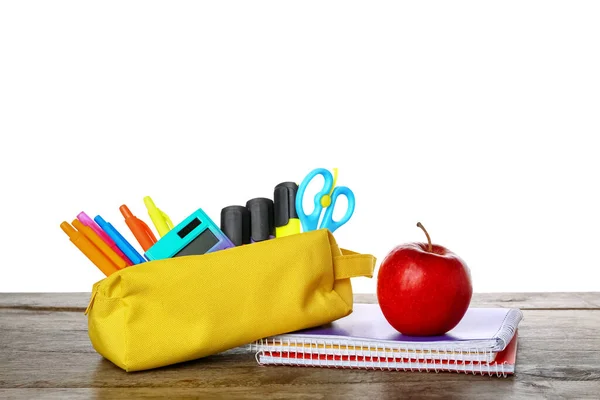 Pencil case with school stationery and apple on table against white background