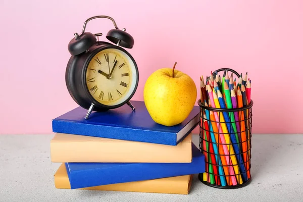 学校文具 桌上有苹果和闹钟 背景是粉色的 — 图库照片