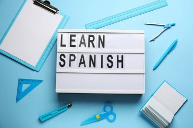 Açık mavi arkaplan üzerinde LEARN SPANISH ve kırtasiye tahtası, üst görünüm