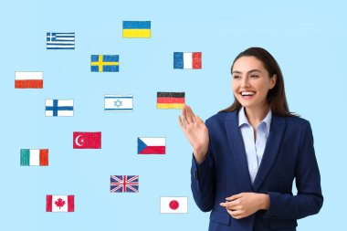 Pretty young businesswoman and different flags on light blue background. Studying of foreign languages
