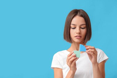 Pretty young woman with makeup sponges on blue background