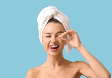 Mavi arka planda küçük makyaj süngeri olan güzel bir genç kadın.