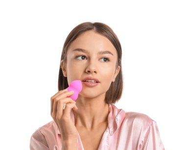 Pretty young woman with pink makeup sponge on white background
