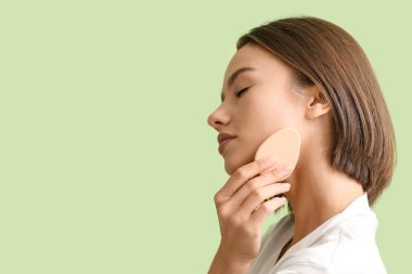 Yeşil arka planda makyaj süngeri olan güzel genç bayan, yakın plan.