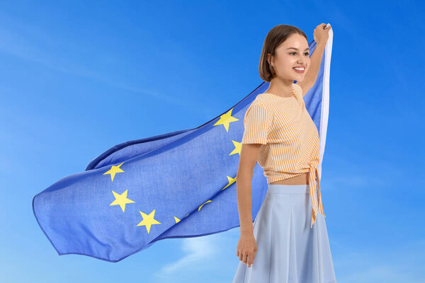 Beautiful young woman with flag of European Union against blue sky