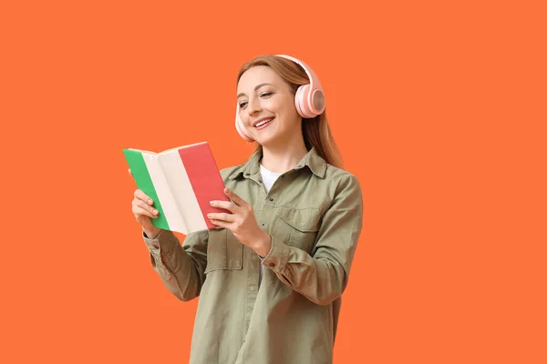 Mature Woman Headphones Reading Book Orange Background Concept Studying Italian — Foto de Stock