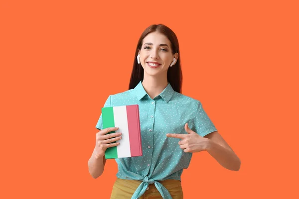 Young Woman Earphones Book Orange Background Concept Studying Italian Language — Zdjęcie stockowe