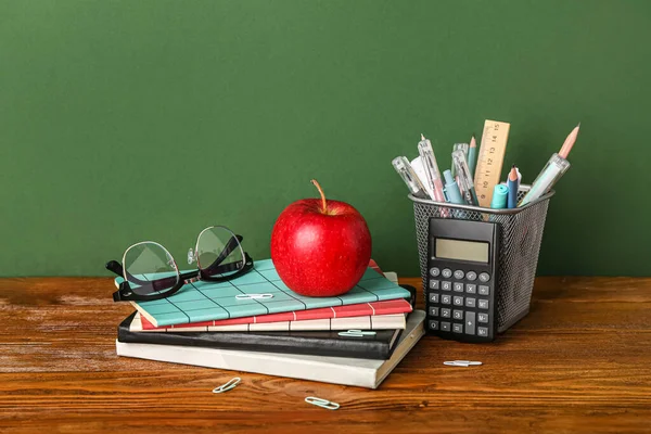 Cancelleria Scolastica Con Mela Occhiali Sul Tavolo Sullo Sfondo Verde — Foto Stock