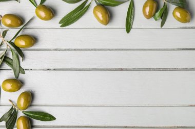 Yeşil zeytinli kompozisyon ve açık ahşap arka planda yapraklar