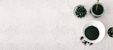 Healthy spirulina powder and pills on light background with space for text