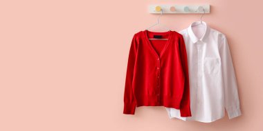Stylish school uniform hanging on color wall. Banner for design