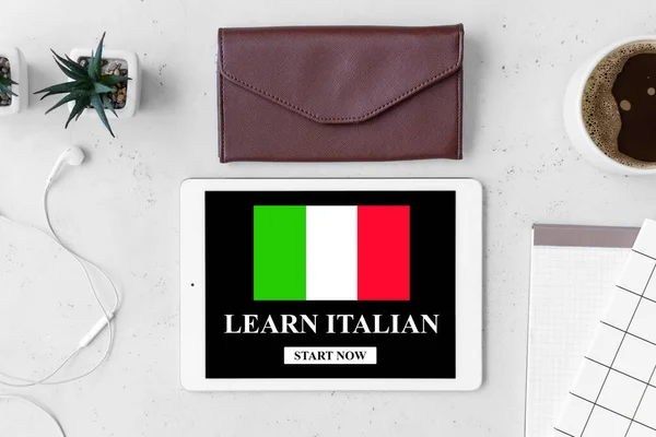 Tablet computer with text LEARN ITALIAN on screen at workplace, top view