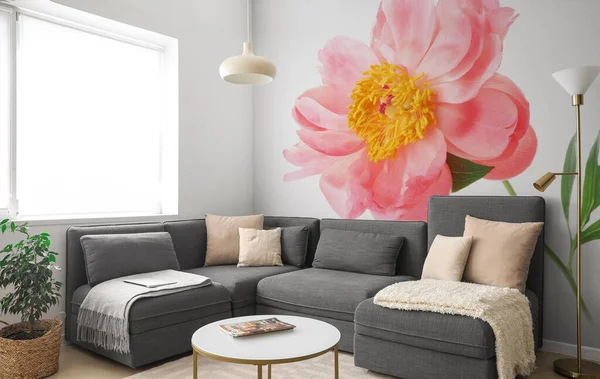 Stylish interior of light living room with grey sofa and printed beautiful flower on wall