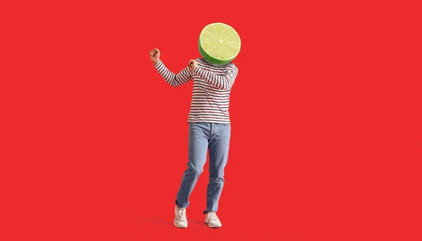 Dancing man with ripe lime instead of his head on red background