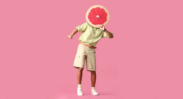 Dancing man with ripe grapefruit instead of his head on pink background