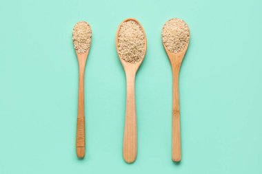 Yeşil arka planda susam tohumlu tahta kaşıklar.