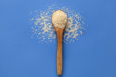 Mavi arka planda susam tohumlu tahta kaşık.