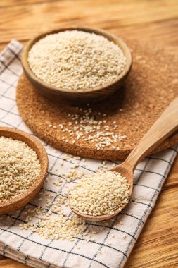 Tahta arka planda susam tohumlu kâseler ve kaşıklar, yakın plan.