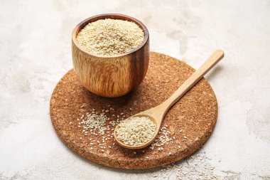 Hafif arka planda kase ve kaşık dolusu susam tohumu.