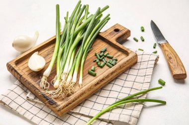 Taze yeşil soğanlı ahşap tahta ve arka planda bıçak.
