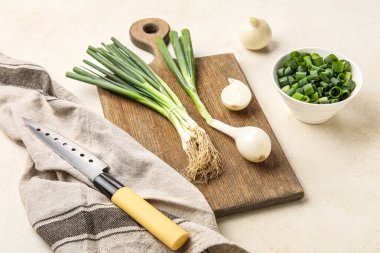 Yeşil soğanlı ahşap tahta ve arka planda bıçak.