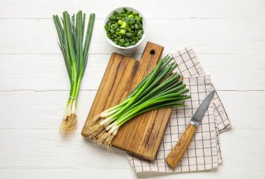 Açık ahşap zemin üzerinde taze soğan ve bıçak kompozisyonu