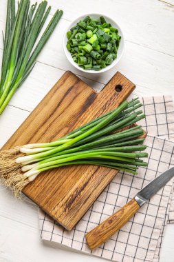 Açık ahşap zemin üzerinde taze soğan demeti olan tahta.