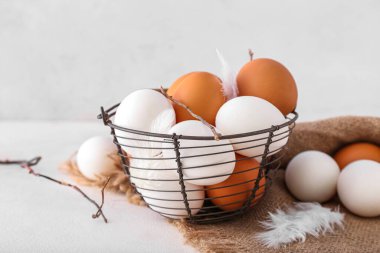 Basket with different chicken eggs on light background